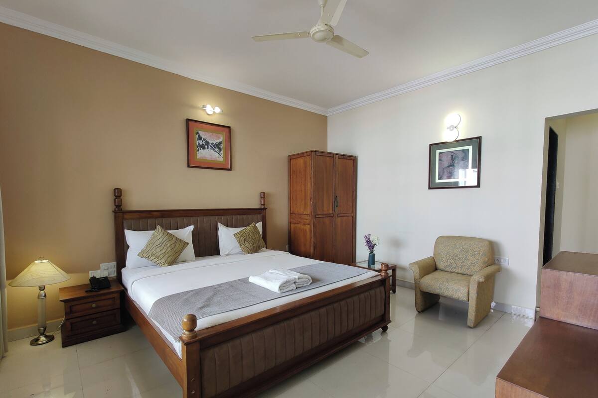 A hotel room with a wooden bed, a wardrobe, a chair, and a desk.