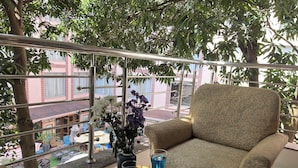 Un balcone con un divano, un tavolino in vetro e un vaso con fiori.