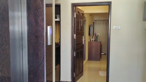 Un corridoio con pavimento in marmo, una porta in legno e una parete bianca con telecamera di sicurezza.