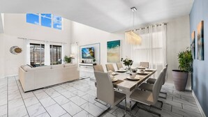Een moderne woonkamer met een bank, eettafel, stoelen en een televisie.