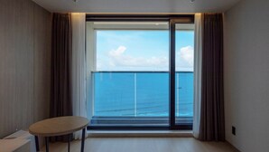 Una habitación con un amplio ventanal corredero que da a un balcón con vistas al mar.