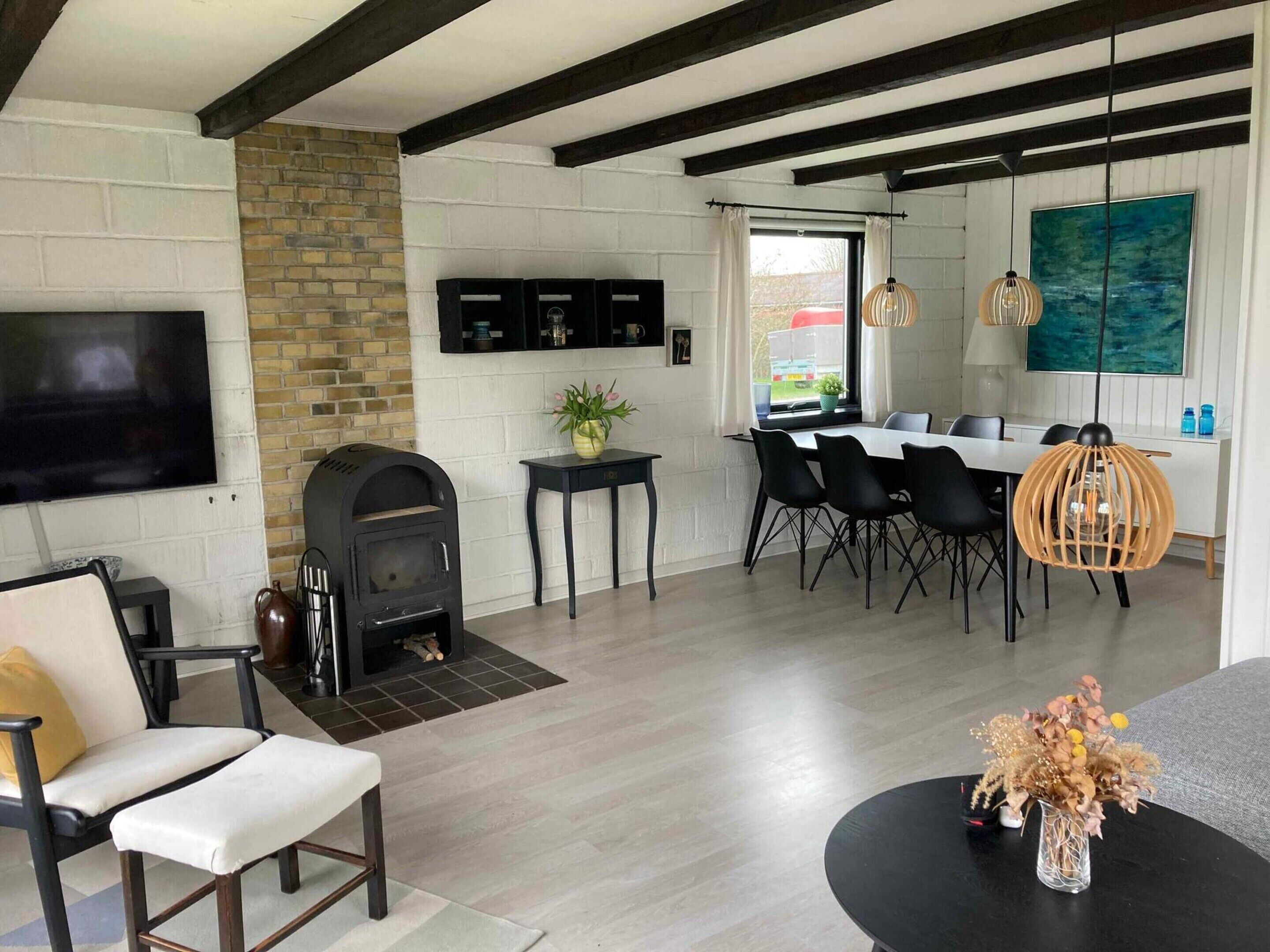Una sala de estar moderna con chimenea, comedor y televisor montado en la pared.