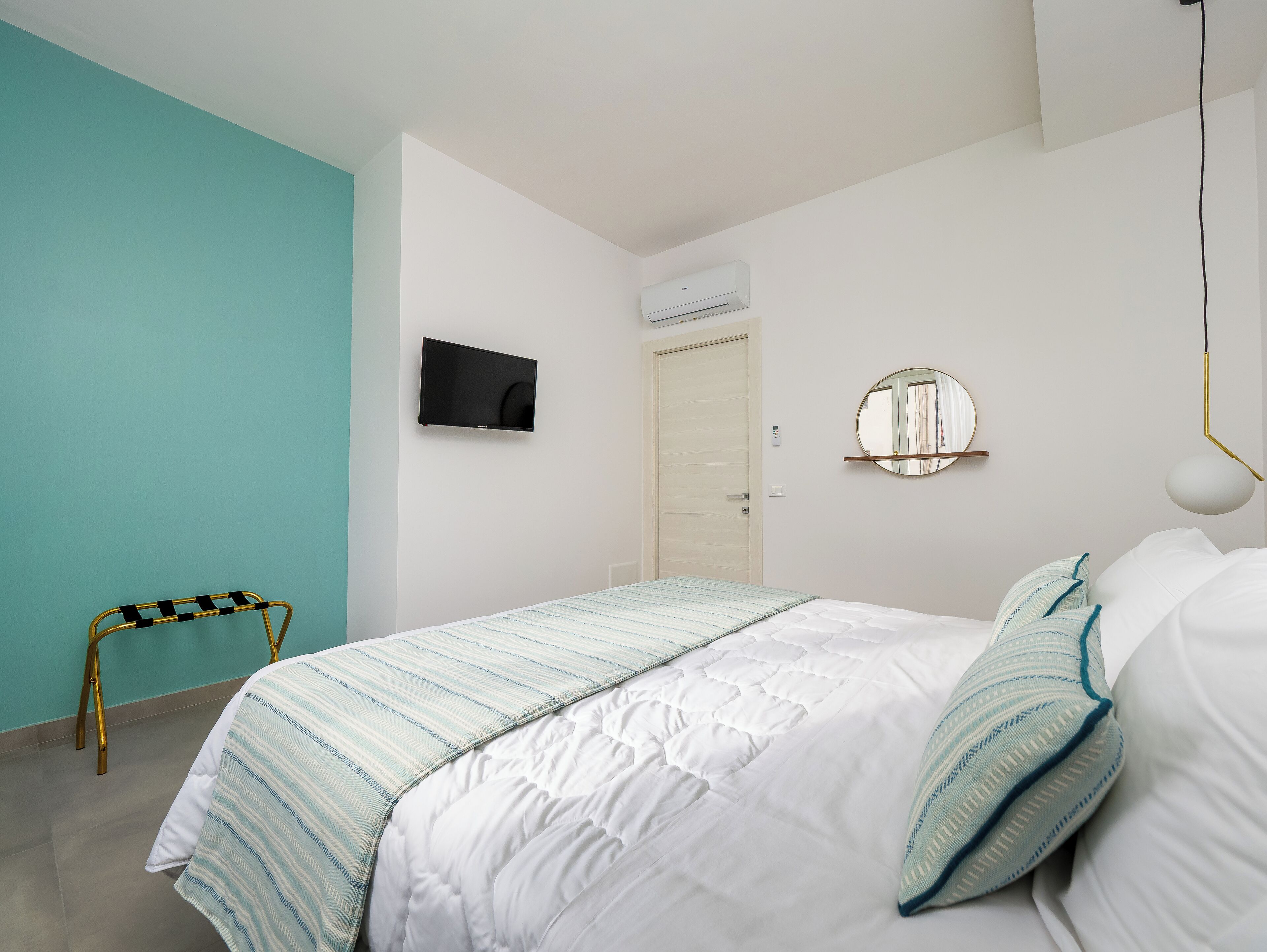 A bedroom with a bed, a TV, a mirror, and a chair.