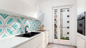 A modern kitchen with white cabinets, a black sink, and a patterned backsplash. - Amal & Surya apartments (Sorrento)