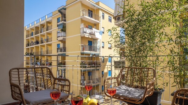 A balcony with wicker chairs, a glass table, and potted plants. - Amal & Surya apartments (Sorrento)