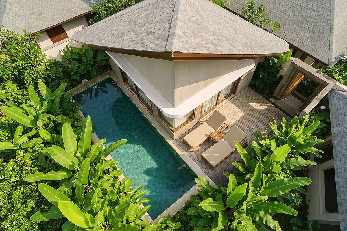 Una casa moderna con piscina, rodeada de exuberante vegetación.