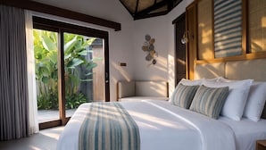 A bedroom with a large bed, a sliding glass door to a garden, and a decorative wall piece. - LaChuba Villas Canggu (Canggu)