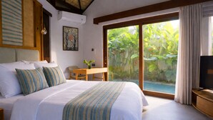 A hotel room with a large bed, a TV, a desk, and a sliding glass door leading to a garden. - LaChuba Villas Canggu (Canggu)