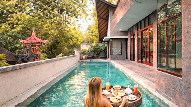 A poolside area with a dining setup, a red pavilion, and a modern building with large windows. - LaChuba Villas Canggu (Canggu)