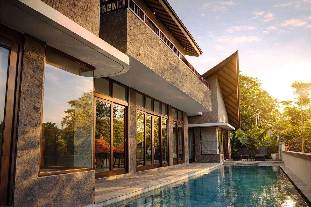 Una casa moderna con piscina, ventanas amplias y un balcón.