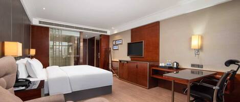 Une chambre d’hôtel équipée d’un lit, d’un bureau, d’une chaise, d’une télévision et d’un mini-bar.