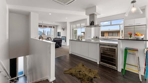 Een moderne keuken met witte kasten, een inbouwoven en een groot raam dat voor natuurlijk licht zorgt.