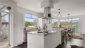 Een moderne keuken met een groot eiland, ingebouwde apparatuur en grote ramen met uitzicht op de omgeving.