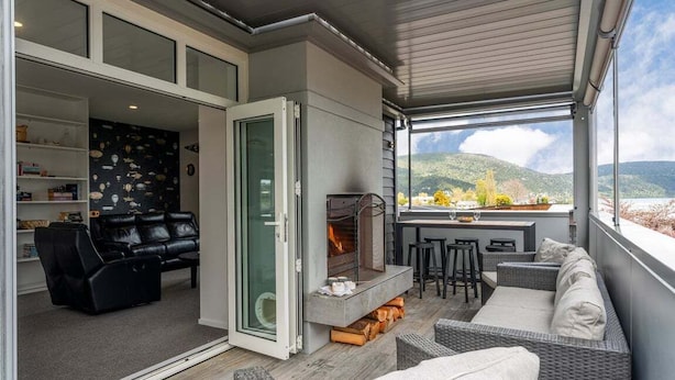 Een moderne woonkamer met een open haard, comfortabele zitplaatsen en uitzicht op de omgeving.
