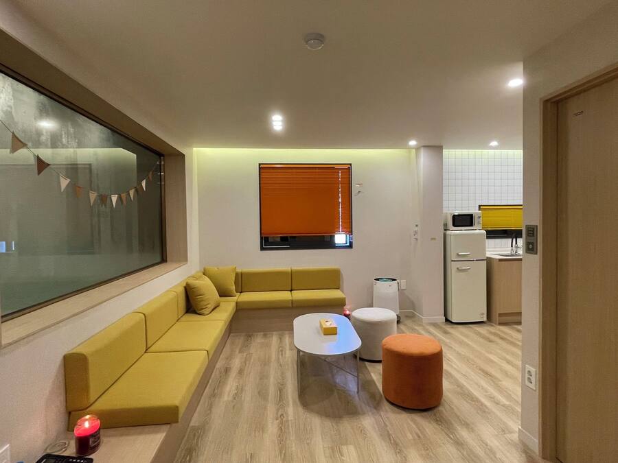 A modern living room with a sofa, a coffee table, and a kitchen area in the background.