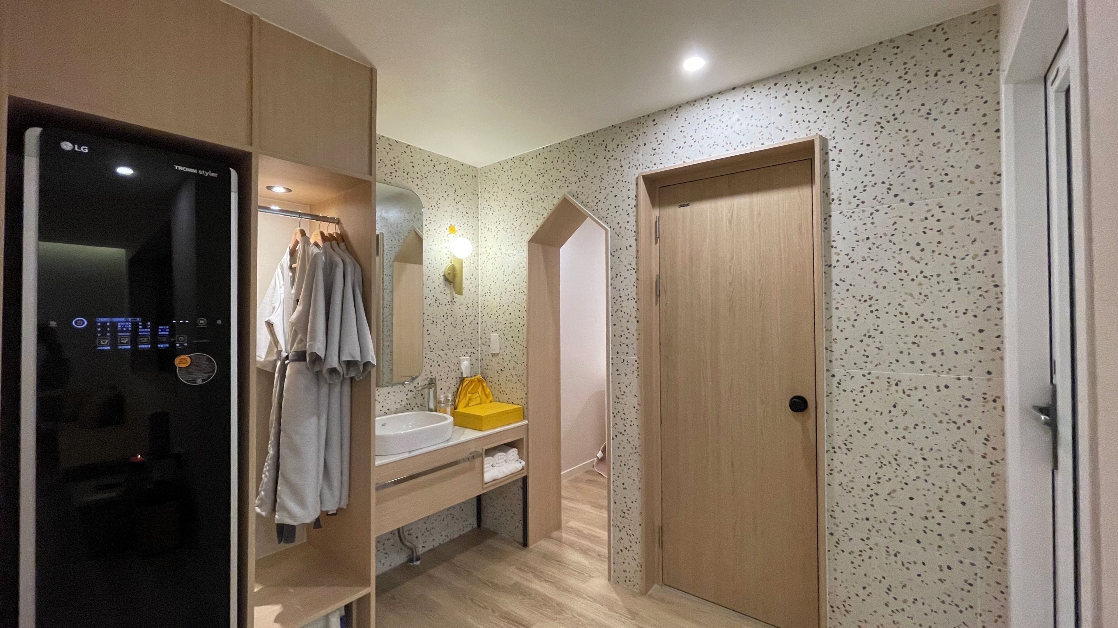 Une salle de bain moderne dotée d’un miroir encastré de la marque LG, d’un meuble-lavabo en bois et d’un espace douche.