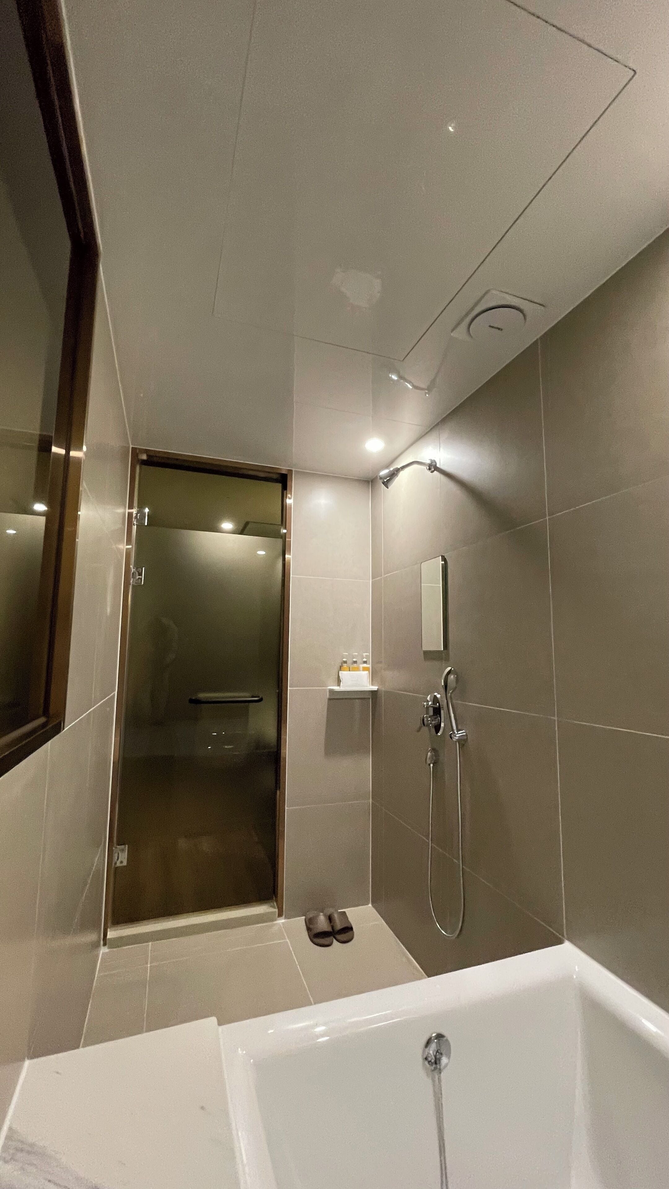 Un baño moderno con bañera, ducha y puerta de vidrio que da a un vestidor ducha.