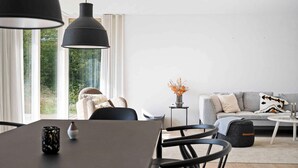 A modern living room with a dining area, featuring a sofa, a coffee table, and a dining table with chairs. - 5 Star Holiday Home in Aakirkeby (Akirkeby)