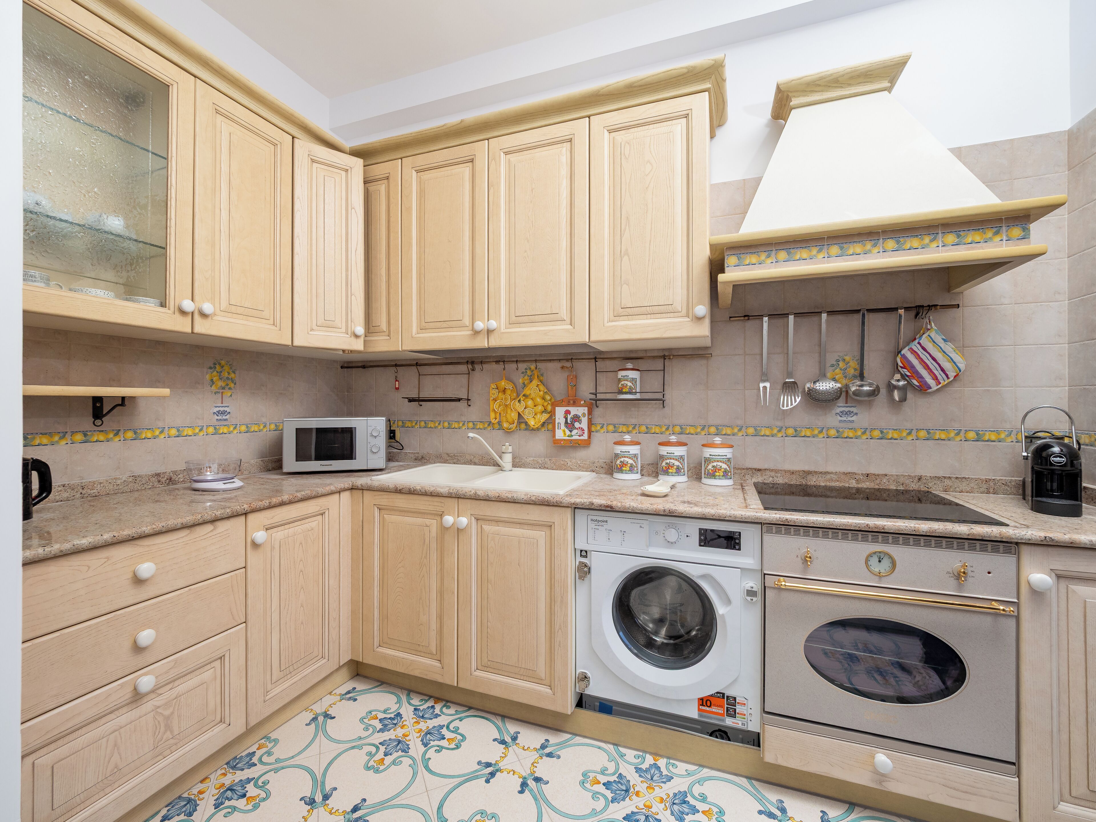 A kitchen with wooden cabinets, a microwave, a washing machine, and an oven.