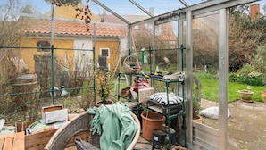 A greenhouse with a glass roof, various gardening tools, and plants. - 5 Star Holiday Home in Ronne (Ronne)