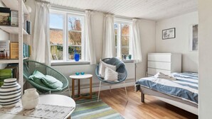 A cozy bedroom with a bed, a chair, a small table, and a bookshelf. - 5 Star Holiday Home in Ronne (Ronne)