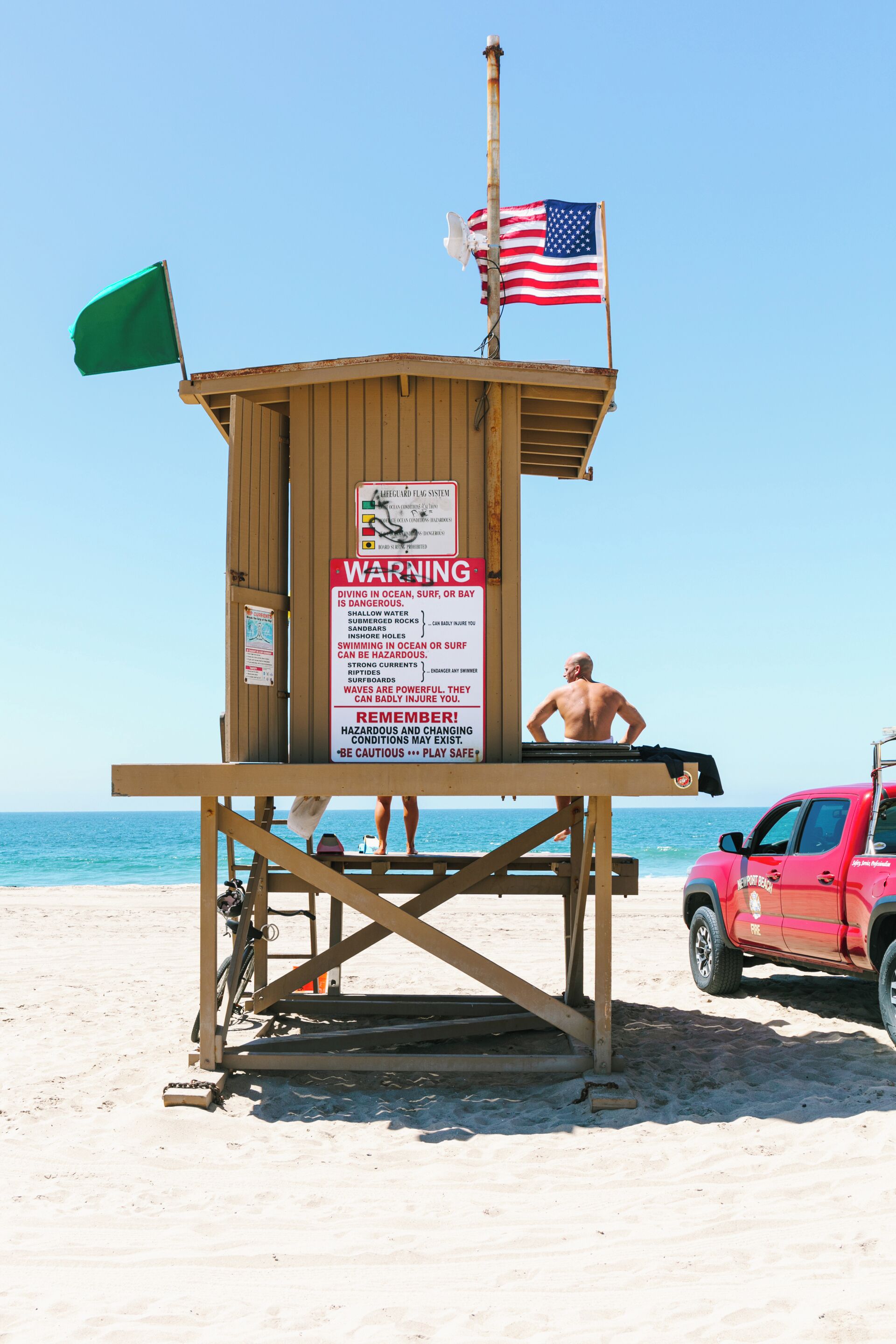 Een redderstoren met een Amerikaanse vlag, waarschuwingsborden en een strandstoel voor de redder.
