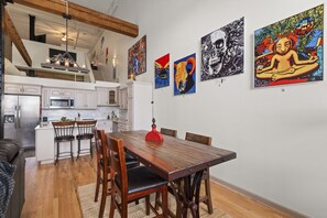 A modern kitchen with white cabinets, stainless steel appliances, and a wooden dining table with chairs.
