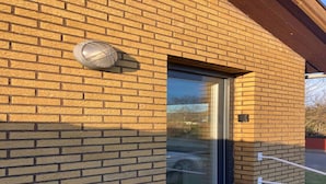 Un edificio de ladrillo con puerta de vidrio y una cámara de seguridad montada en la pared.
