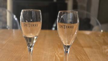 Dos copas de vino vacías con el nombre de marca "DeTerre" sobre una mesa de madera.