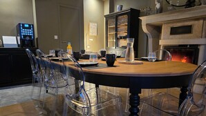 A dining area with a round table, clear chairs, a cabinet with glass doors, and a fireplace.