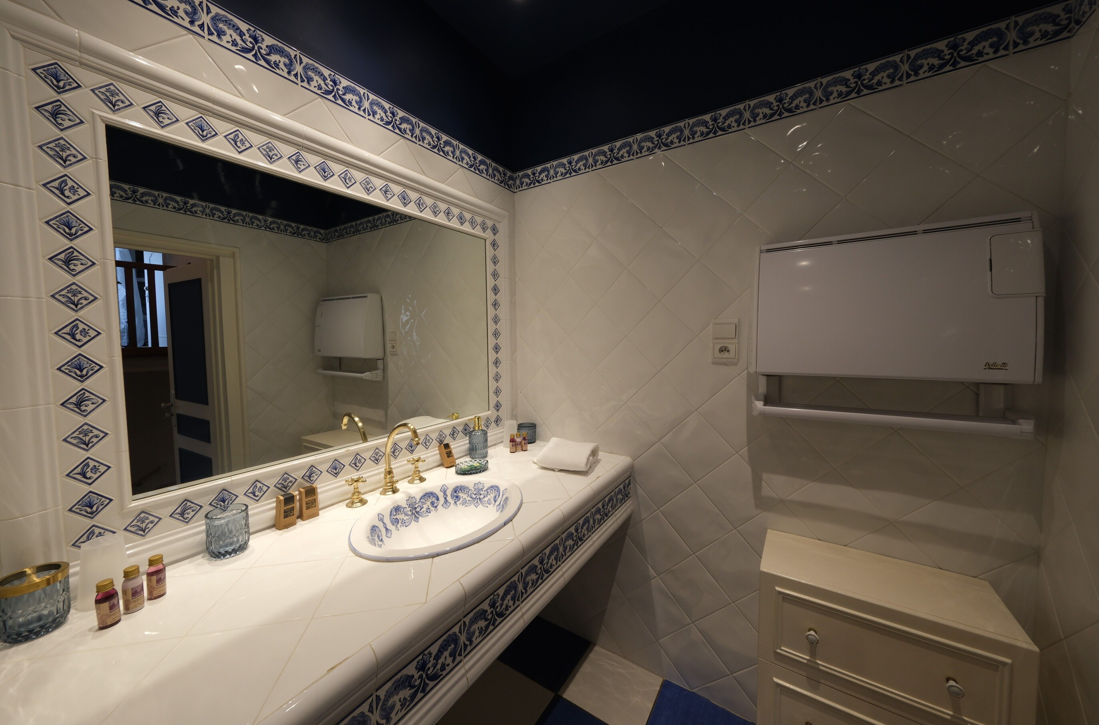 A bathroom with a white sink, blue and white tiles, a mirror, and a towel rack.