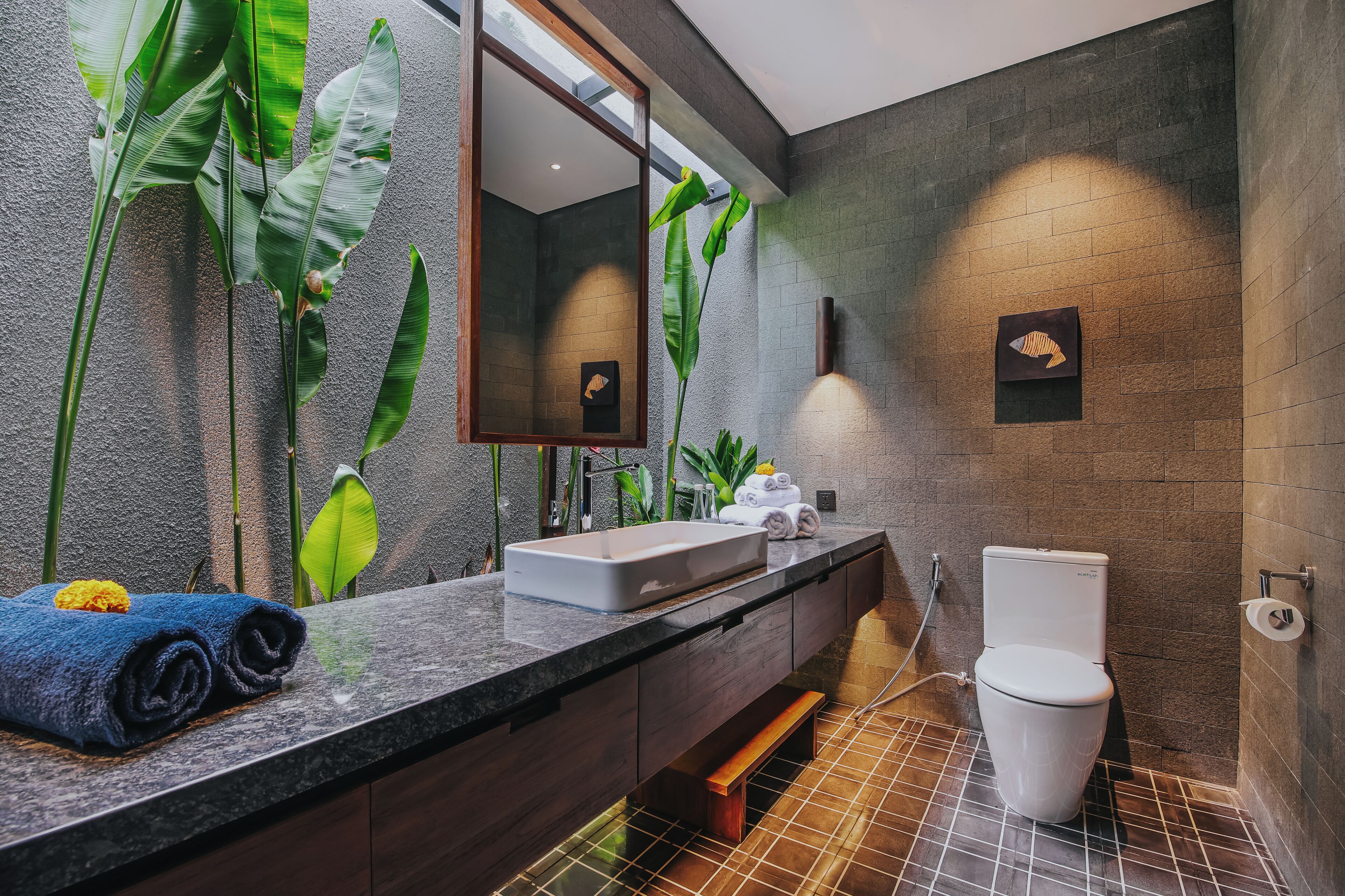 A modern bathroom with a large mirror, a sink, and a toilet.