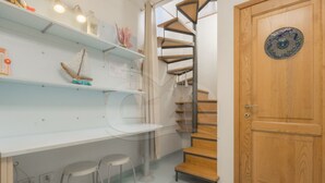 Eine moderne Küche mit weißen Arbeitsplatten, einer eingebauten Wendeltreppe und einer Holztür mit einer verzierten Platte.
