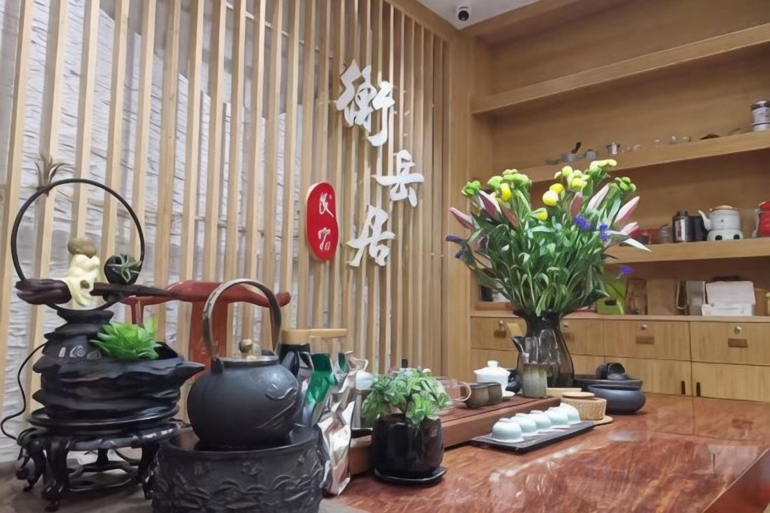 Un juego de té tradicional, una tetera y un florero con flores sobre una mesa de madera.