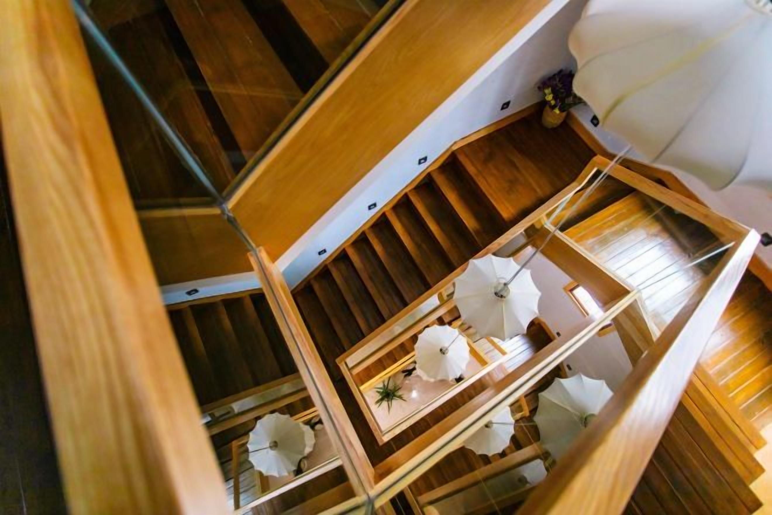 A wooden interior with a staircase, a hanging light fixture, and a framed artwork.