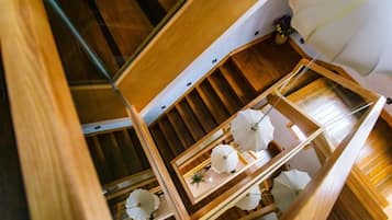 A wooden interior with a staircase, a hanging light fixture, and a framed artwork.