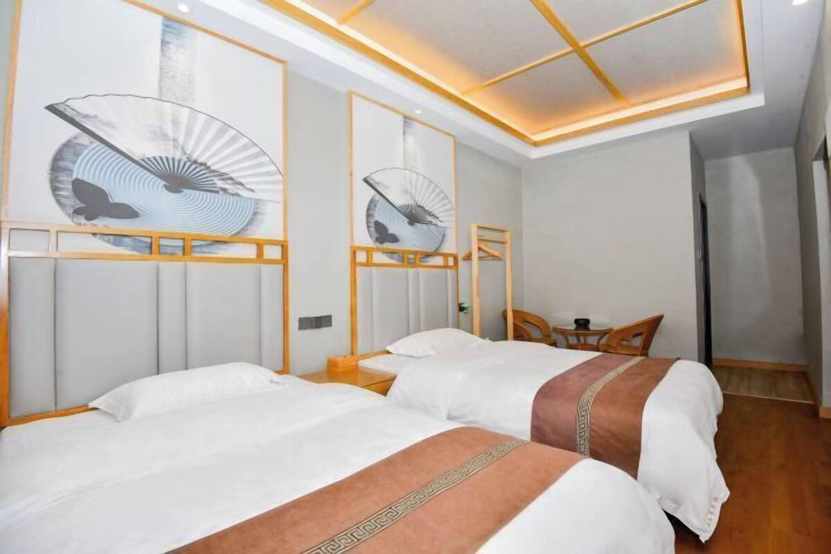 A hotel room with two beds, a small table, chairs, and artwork on the walls.