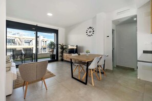 Un comedor moderno con una mesa y sillas de madera, un televisor y un reloj en la pared.