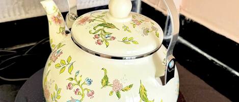 A floral-patterned electric kettle on a black stovetop.