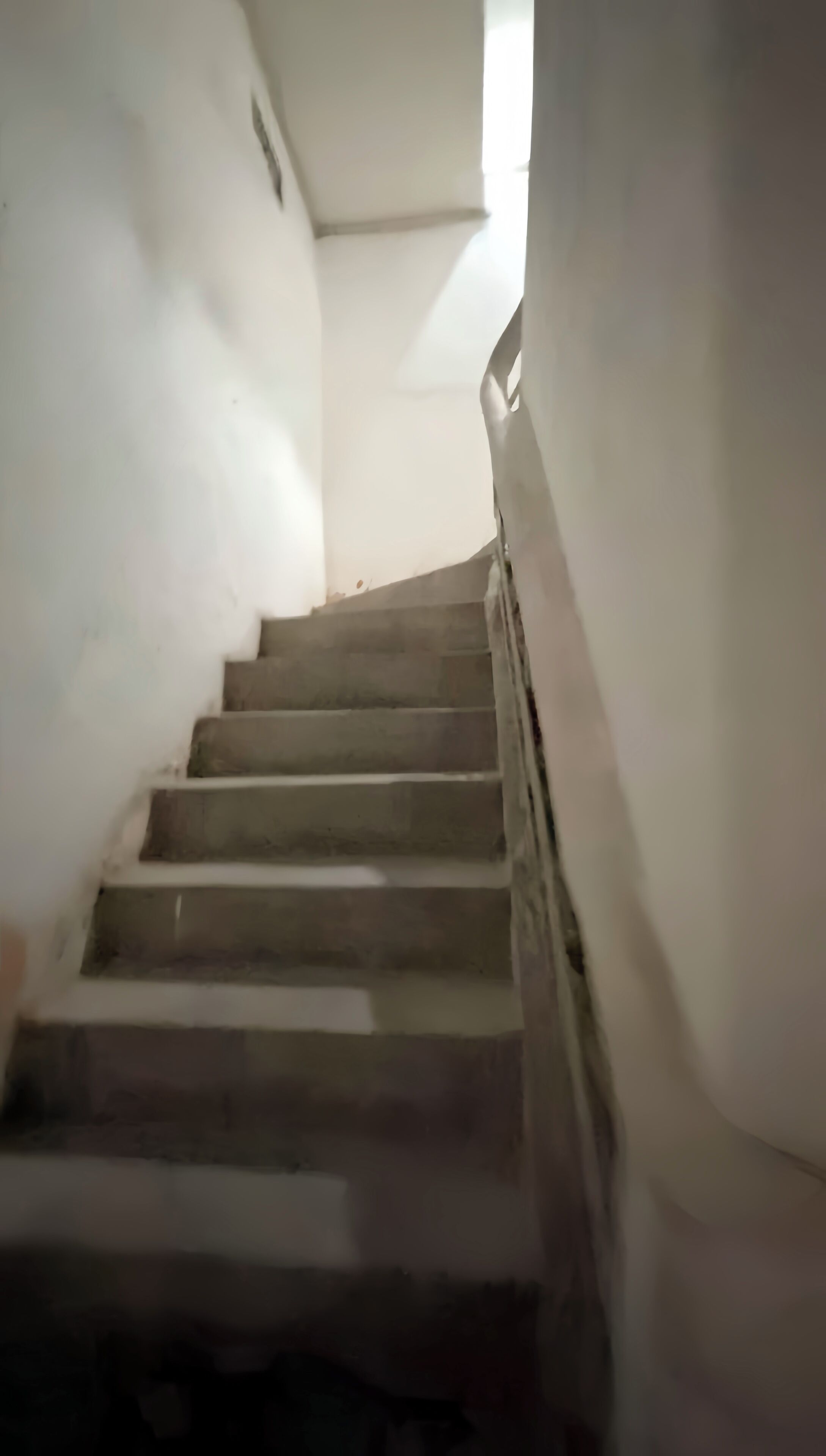 Una escalera con barandilla que conduce a una plataforma con ventanal.