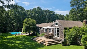 Une maison dotée d’une terrasse, d’une piscine et d’une pelouse bien entretenue.