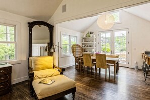 A spacious room with a large mirror, a dining area with chairs and a table, and a bookshelf.