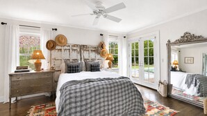 Une chambre à coucher avec un lit, une commode, un miroir et un ventilateur de plafond.