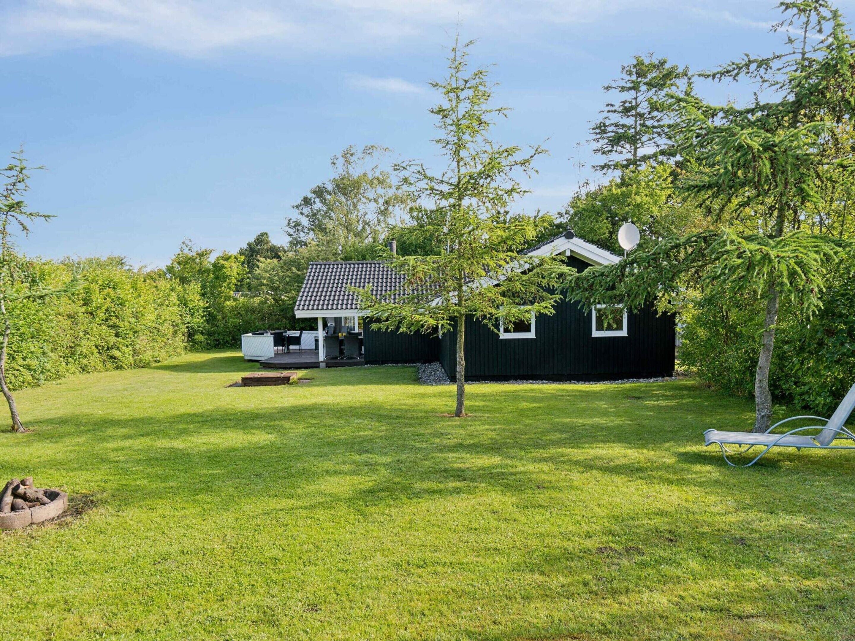 Uma casa com varanda coberta, gramado e árvores.