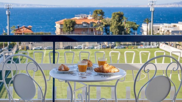A balcony with a table set for breakfast, overlooking a coastal view with buildings and the sea. - Casa Cafarelli - Bright apt with Stunning view (Sorrento)