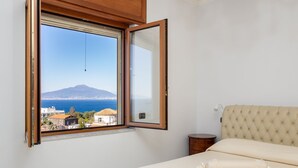 A bedroom with a bed, a bedside table, a nightstand, a window with an open view of a mountain and sea. - Casa Cafarelli - Bright apt with Stunning view (Sorrento)