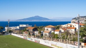 A coastal town with a stadium, buildings with red-tiled roofs, and a mountain in the background. - Casa Cafarelli - Bright apt with Stunning view (Sorrento)