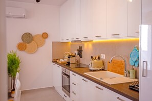 A modern kitchen with white cabinets, a wooden countertop, and a built-in oven. - Colors of Mykonos, Ano Mera, lovely apartment. (Mykonos)