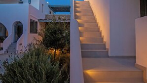 Ein modernes Gebäude mit einer Treppe, die zu einer zweiten Etage führt, umgeben von weißen Wänden und Grünpflanzen.