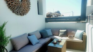 Ein Balkon mit einer Couch, zwei Beistelltischen und einer Wanddekoration.
